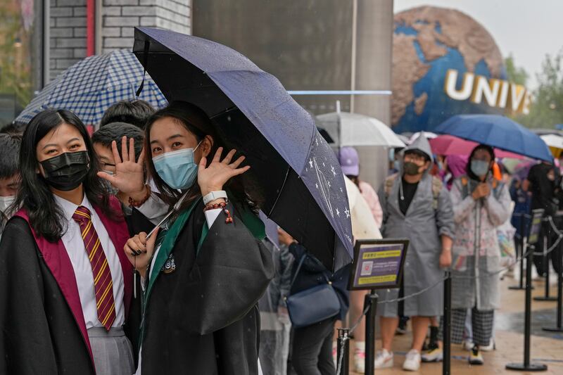 Women wear face masks to help protect themselves from Covid-19 as they line up to enter a merchandise store at Universal Studios Beijing. AP Photo