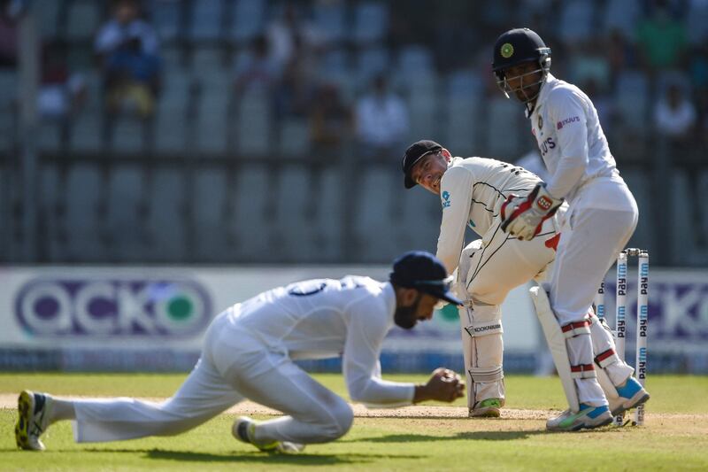 India's Cheteshwar Pujara takes a catch to successfully dismiss New Zealand batsman Tom Blundell for eight off the bowling of Ravichandran Ashwin. AFP