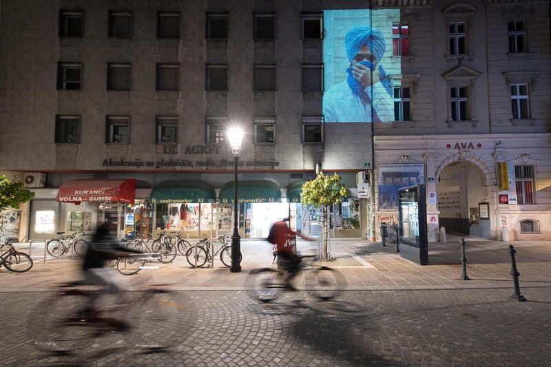 SLOVENIA: People ride their bicycles as a photograph by local photographer Ciril Jazbec is projected on a facade in Ljubljana on April 16, 2020, amid the outbreak of coronavirus. Galleries are closed due to the outbreak, so a group of photographers decided to exhibit their works in a slideshow projected on facades and other public spaces. AFP