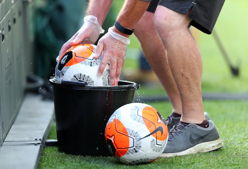A member of staff disinfects a match ball. Getty