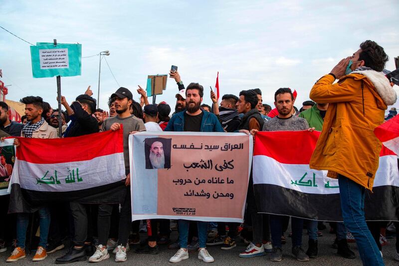 Protesters march with Iraqi national flags and a sign showing a quote from Iraq's top Shiite cleric Grand Ayatollah Ali Sistani reading in Arabic "Iraq is sovereign over itself, the people have had enough suffering from warfare, troubles, and hardships", during an anti-government demonstration, also calling for freedom of the press, in the southern Iraqi city of Basra.  AFP