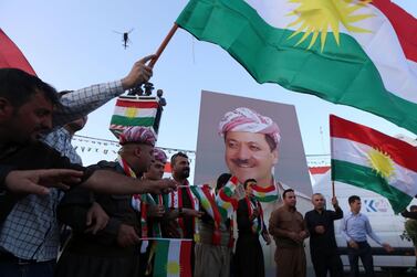 Iraqi Kurds wave Kurdish flags next to a poster of Masoud Barzani, their former president, in Erbil. AFP