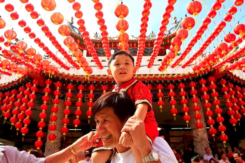 A man carries his child under traditional Chinese lanterns at a temple in Kuala Lumpur, Malaysia. Sadiq Asyraf / AP Photo