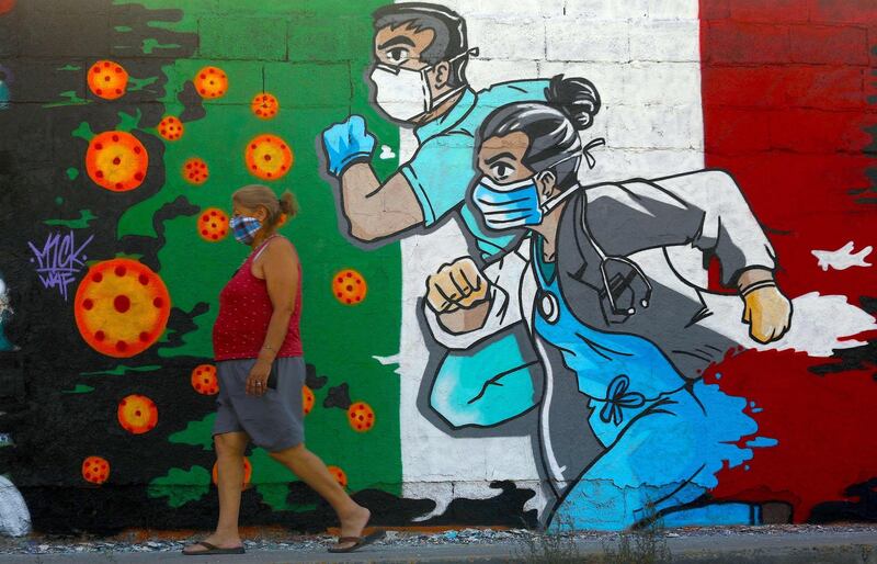 A woman walks past a coronavirus-related mural painted by artist Mick Martinez in Ciudad Juarez, state of Chihuahua, Mexico. AFP