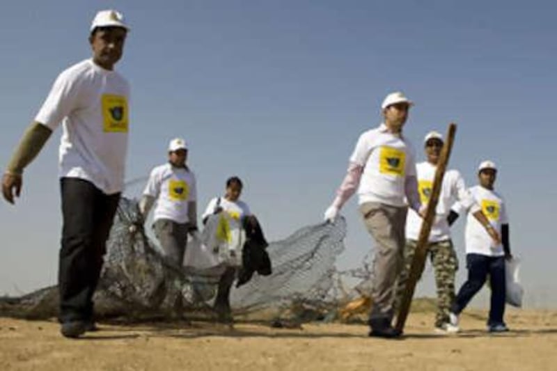 Volunteers from "Rice and Spice", part of the Taste Department of the Jumeirah Group, carry rubbish they've collected in the desert