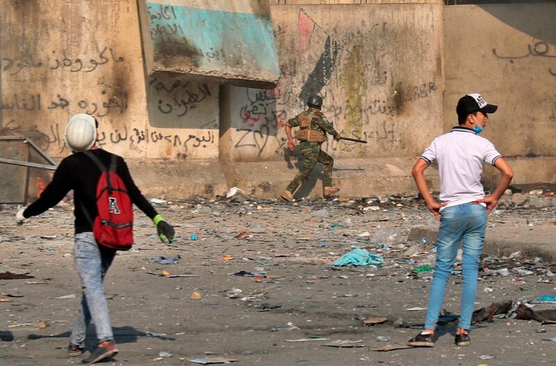 A soldier runs for cover while anti-government protesters throw stones and Molotov cocktails during clashes on Rasheed Street, Baghdad. AP Photo