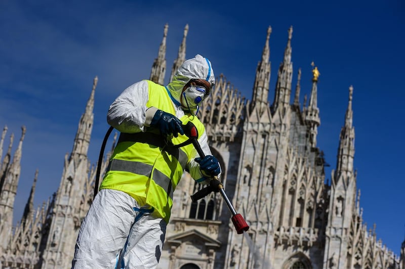 TOPSHOT - An employee wearing protective gear, working for environmental services company AMSA, sprays disinfectant on Piazza Duomo in Milan, on March 31, 2020 during the country's lockdown aimed at curbing the spread of the COVID-19 infection, caused by the novel coronavirus.  / AFP / Piero Cruciatti
