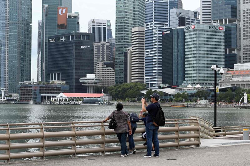 A man takes a photo as the financial business district looms in the background in Singapore on January 2, 2020. Singapore's trade-reliant economy grew 0.8 percent in the fourth quarter to December, according to advance estimates by the trade ministry on January 2. / AFP / Roslan RAHMAN
