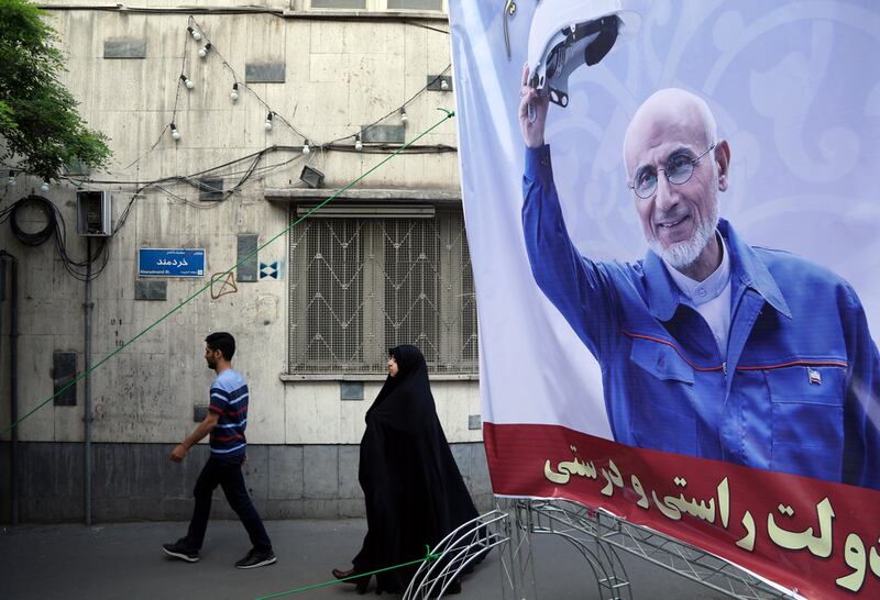 Iranians walk behind a huge election campaign poster of Iranian presidential conservative candidate Mostafa Mir-Salim in front of his office in Tehran, Iran, 23 April 2017. .  EPA/ABEDIN TAHERKENAREH