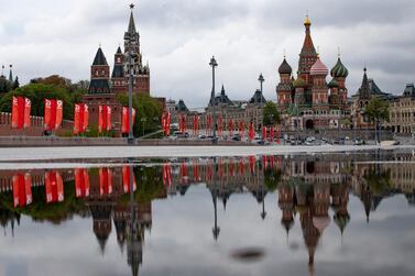 The Kremlin Wall with Spasskaya Tower, left, and St. Basil's Cathedral are reflected in a rainwater on the almost empty Bolshoy Moskvoretsky bridge decorated with red flags prior to celebrating Victory Day in Moscow AP