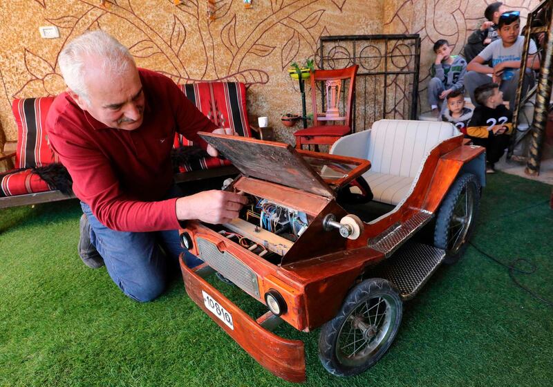 Palestinian Fawzi Al Natsheh checks his handmade electric car named "corona" in the West Bank town of Hebron. Fawzi used to work in Israel but is temporarily out of work as a result of the coronavirus  COVID-19 pandemic. He collected iron pipes to make the body and decorated it with wood and painting.  AFP