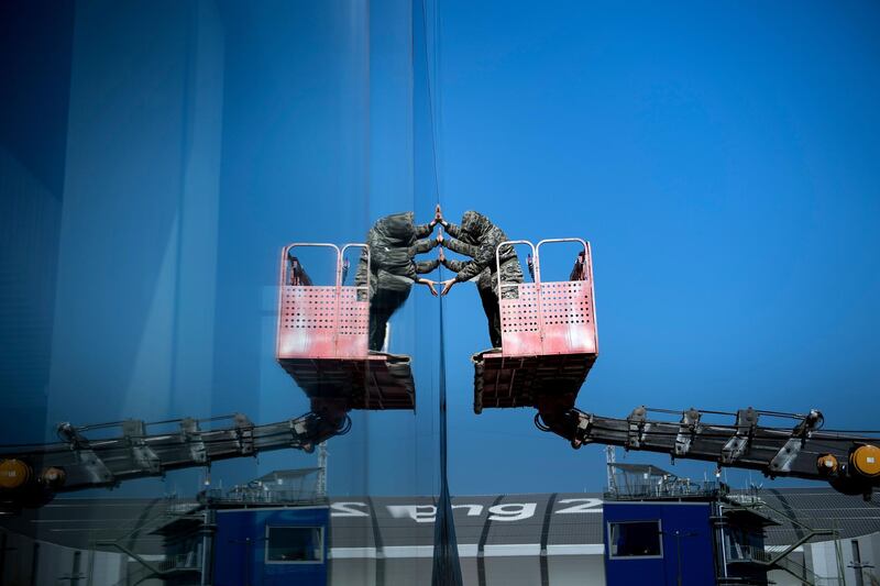 Workers apply tinting to a building's windows in the Gangneung Olympic Park as preparations for the Pyeongchang 2018 Winter Olympic Games continue. Brendan Smialowski / AFP