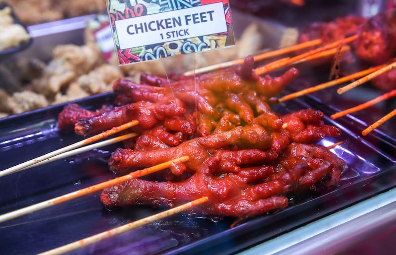 Barbecued chicken feet at Kabayan Zone. The chicken is dipped in a sauce containing garlic, onions and vinegar with red hot chilli peppers. A popular staple in Filipino street food, chicken feet are commonly known as 'adidas', after the sports shoe brand.