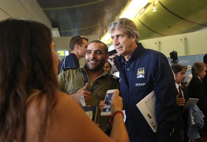 Manuel Pellegrini stops to have his photo taken with Manchester City fans on arrival in Abu Dhabi. Courtesy EAA