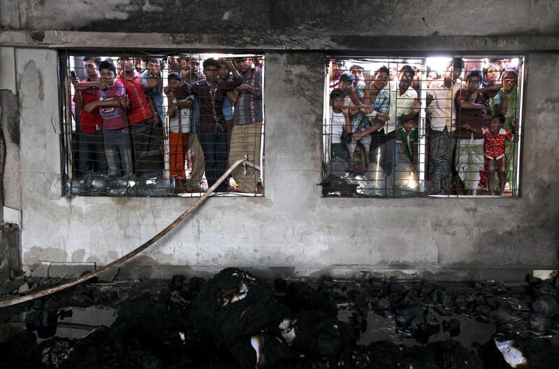 People watch the rescue operation after a devastating fire at the dyeing section of two-storey Aswad Composite Mills at Maona, Gazipur, Bangladesh. Abir Abdullah / EPA