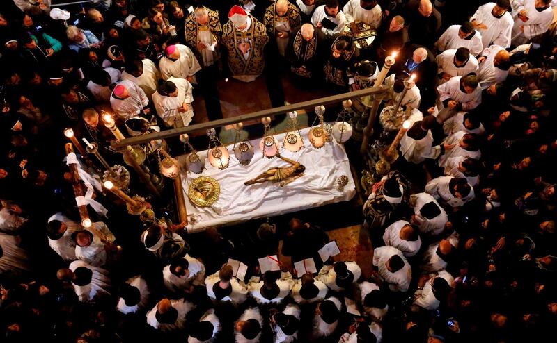 TOPSHOT - Franciscan friars pray over the statue of Jesus lying down on the Anointing Stone during a reenactment of the Funeral of Jesus inside the Church of the Holy Sepulchre during the Good Friday, in the Old City of Jerusalem, on April 19, 2019.  Thousands of Christian pilgrims attend the funeral of Jesus where, according to the tradition, Jesus Christ was crucified, died and resurrected. / AFP / THOMAS COEX
