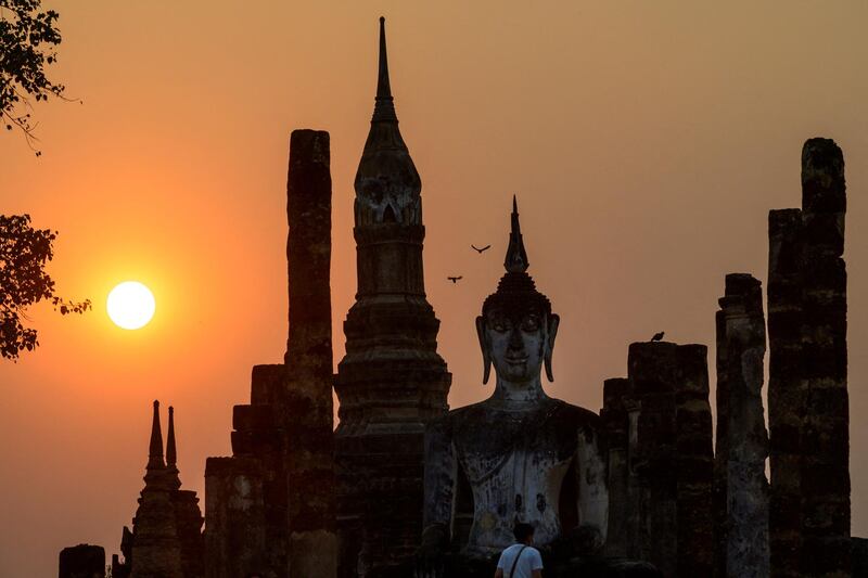 A tourist looks at the Buddha statue at Wat Mahathat during sunset in the Sukhothai Historical Park in northern Thailand. AFP