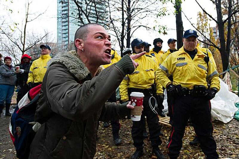 An Occupy Toronto protester reacts to City of Toronto workers who were clearing structures and tents, accompanied by Toronto Police at the Occupy Toronto site in St. James Park in Toronto on Wednesday, Nov. 23, 2011. (AP Photo/The Canadian Press, Nathan Denette)