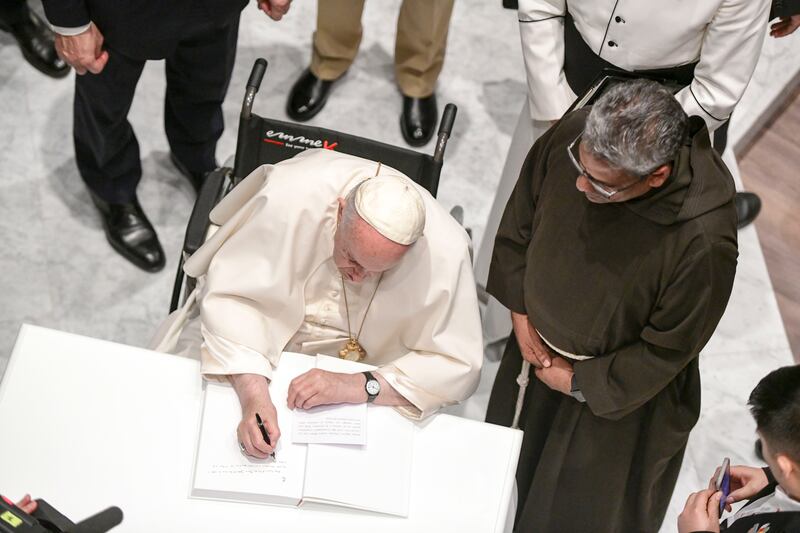 Pope Francis writes in the visitors' book at the cathedral. Khushnum Bhandari / The National
