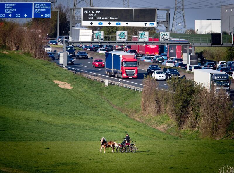 A man rides his horse and carriage over a meadow near the highway in Frankfurt, Germany. Michael Probst / AP Photo