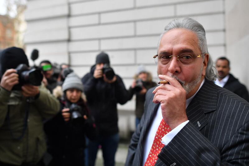 Indian tycoon Vijay Mallya smokes outside court for a break as he attends a hearing at Westminster Magistrates Court in central London on December 10, 2018, where a decision is expected on his extradition case.  Vijay Mallya, a business tycoon who owned a Formula One team, is subject to an extradition request from India, where he left 2016, accused of fraud.  / AFP / Ben STANSALL

