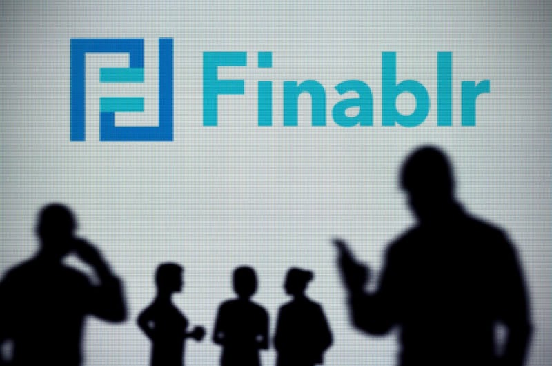 2AA5PG0 The Finablr logo is seen on an LED screen in the background while a silhouetted person uses a smartphone (Editorial use only)
