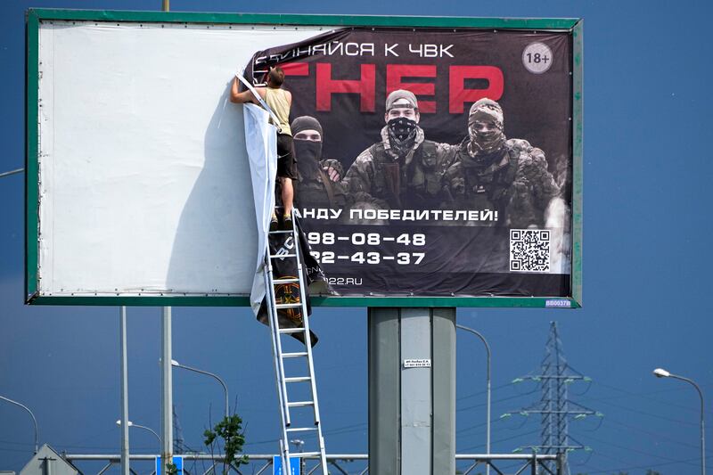 A man takes down the poster with writing reading 'Join us at Wagner' on the outskirts of St. Petersburg. AP Photo