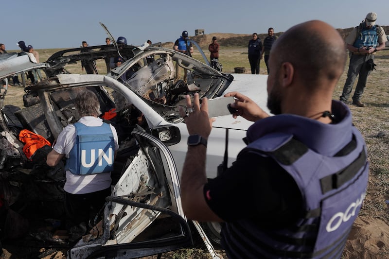 UN staff members inspect the remains of a car used by US-based aid group World Central Kitchen that was hit by an Israeli strike in central Gaza on Monday. AFP