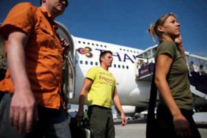 BANGKOK, THAILAND -DECEMBER 03: Passengers exit Thai Airways flight from Phuket, the first to arrive after the end of the seige, lands at Suvarnabhumi International Airport on December 3, 2008 in Bangkok, Thailand. Yesterday, a court dissolved Thailand's top three ruling parties for electoral fraud, banned the prime minister from politics for five years and thus brought down a government that has faced months of protests. Deputy Prime Minister Chaowarat Chanveerakul will become the caretaker prime minister. The on-going political crisis during the holiday season stranded 300,000 foreign tourists, paralysing Thailand's lucrative tourist industry.  (Photo by Chumsak Kanoknan/Getty Images) *** Local Caption ***  GYI0056298797.jpg