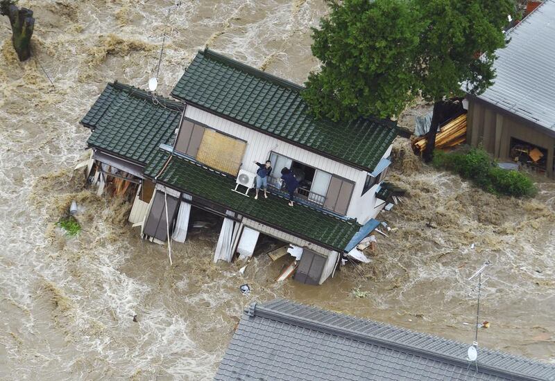 A resident waves from a flooded house in Joso city, north-east of Tokyo, on September 10, 2015. Kyodo News via AP