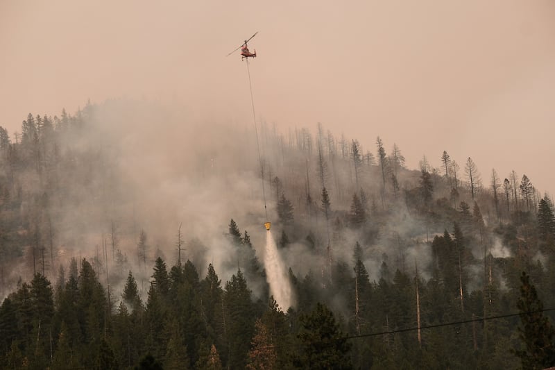 A helicopter drops water on a brush fire in California. Bloomberg