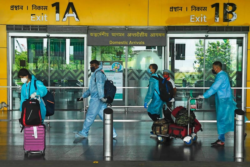 Air passengers wearing protective suits walk out of the arrival lounge of the Netaji Subhas Chandra Bose International Airport after the authorities eased restrictions imposed as a preventive measure against the spread of the COVID-19 coronavirus, in Kolkata on July 6, 2020. India announced on July 6 that it had logged nearly 700,000 coronavirus cases, taking it past Russia to become the world's third-hardest-hit nation in the global pandemic. / AFP / Dibyangshu SARKAR
