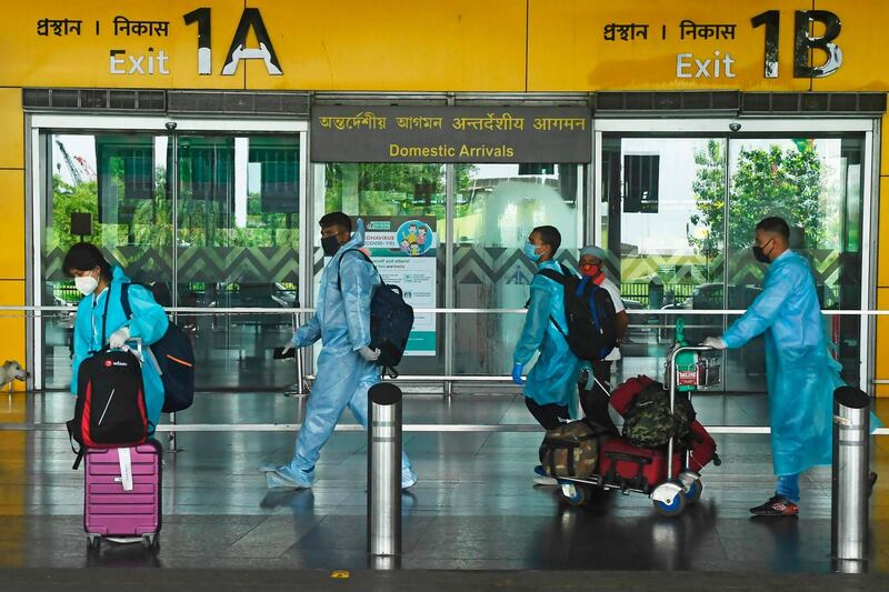 Air passengers wearing protective suits walk out of the arrival lounge of the Netaji Subhas Chandra Bose International Airport after the authorities eased restrictions imposed as a preventive measure against the spread of the COVID-19 coronavirus, in Kolkata on July 6, 2020. India announced on July 6 that it had logged nearly 700,000 coronavirus cases, taking it past Russia to become the world's third-hardest-hit nation in the global pandemic. / AFP / Dibyangshu SARKAR
