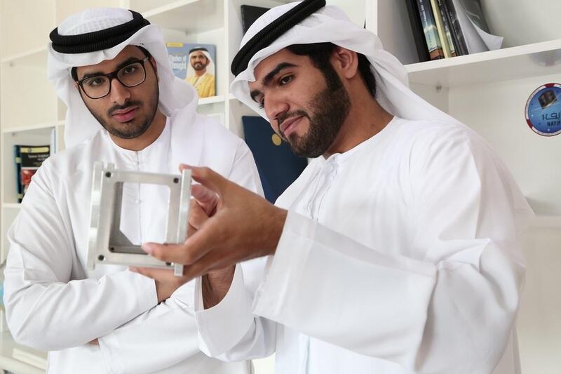 Abdulla Al Shehhi, right, holds the model of the nanosatellite that is now orbiting. With him is Khalifa AlMheiri, communication unit engineer. Courtesy MBRSC