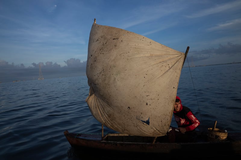 Yohandry Colina uses an oil-stained sheet for a sail on the boat he uses to catch fish in Lake Maracaibo in Cabimas, Venezuela. AP Photo
