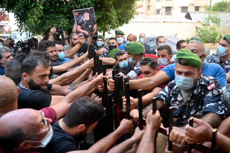 Families and relatives of victims of the August Beirut port explosion clash with Lebanese riot police during a protest outside the Lebanese interior minister's house in Beirut.