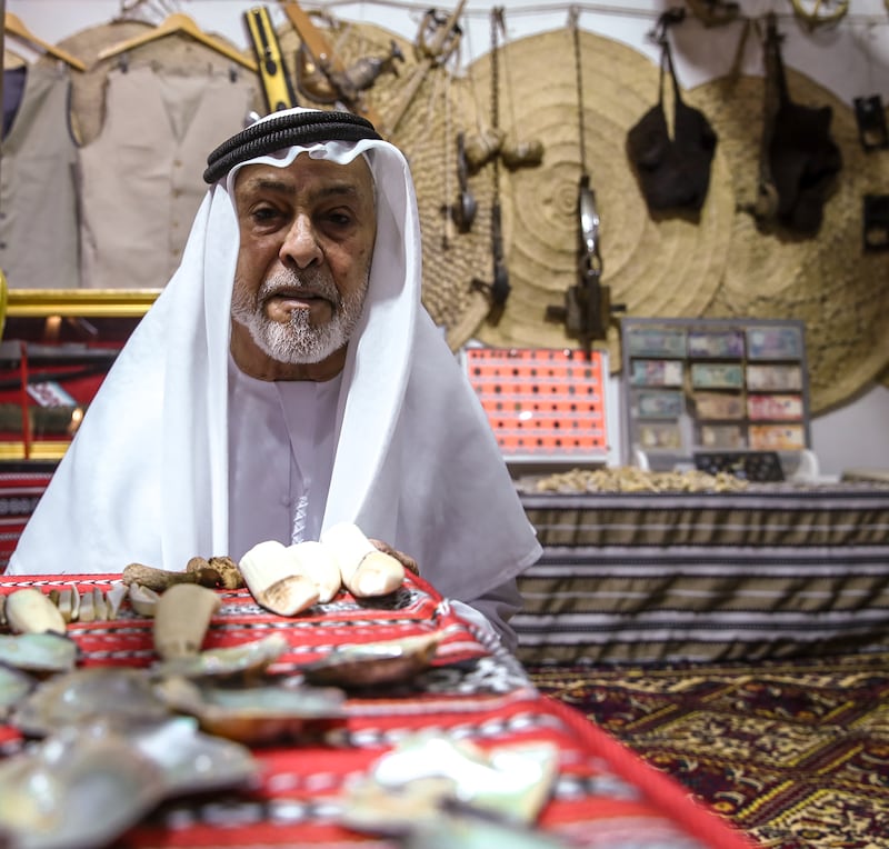 Bin Hathbour sets up his display of old model dhow boats, pearls, wooden clogs and other Emirati traditional items