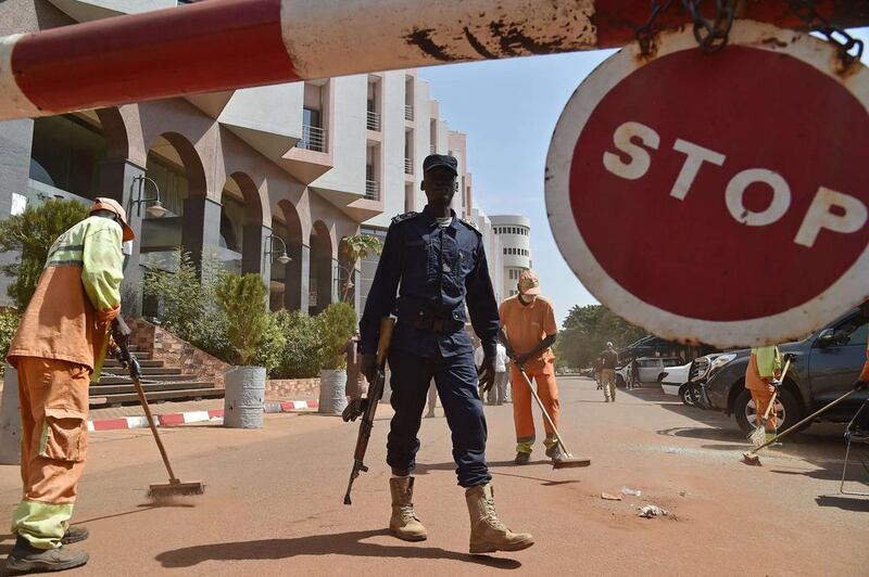 A Malian police officer stands guard as municipal workers clean outside the Radisson Blu hotel in Bamako on November 22, two days after a deadly attack. AFP Photo

