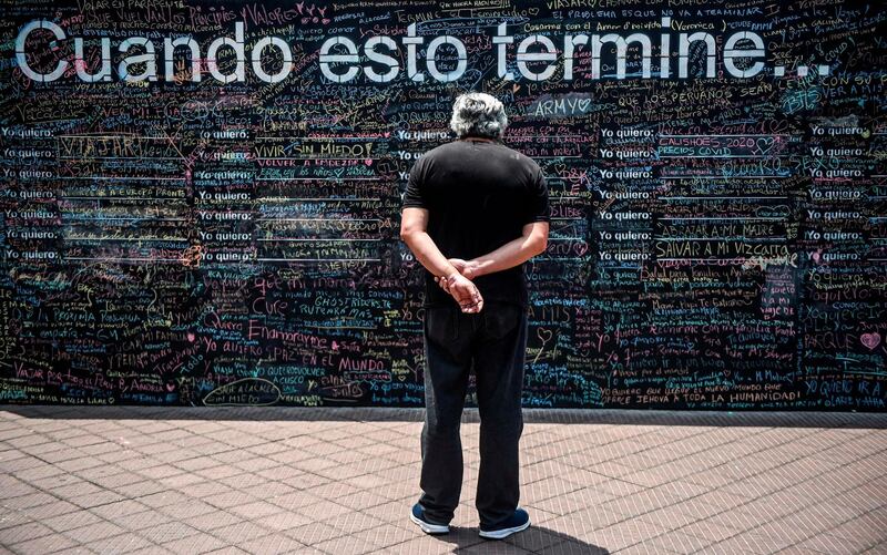 A man looks at a giant blackboard where people write what they want to do when the new coronavirus pandemic is over, in Lima.  On giant blackboards placed in two squares in Lima, people can write with colored chalk what they want to do "when this is over."  AFP