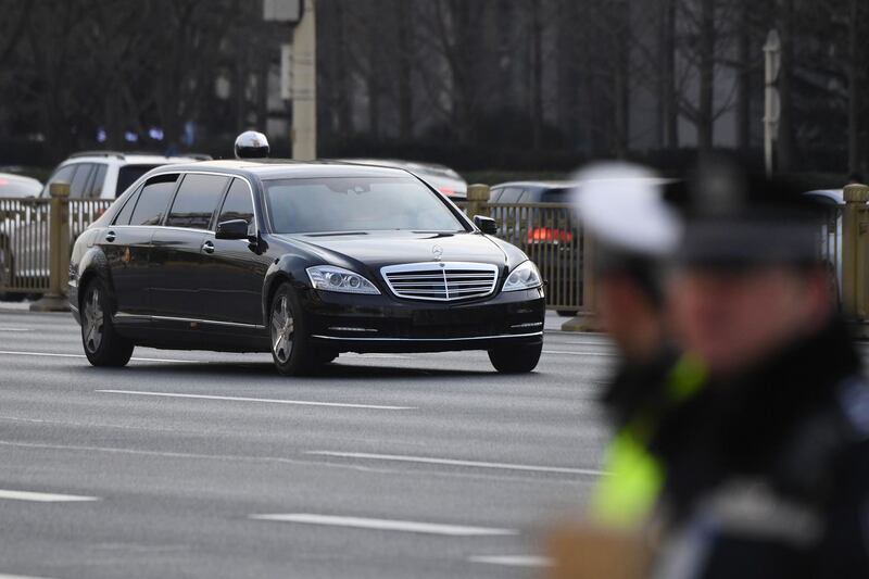 The lead limousine in the motorcade of Kim Jong-un drives past police standing guard along the main east-west boulevard of Changan in Beijing. AFP