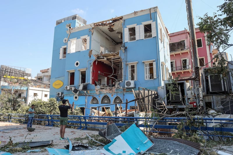 A pedestrian takes photos of a badly damaged building in Beirut. Bloomberg