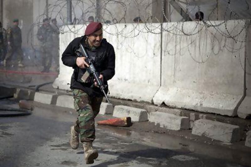 An Afghan soldier runs outside the defence ministry after a suicide bomber attacked outside the ministry, killing at least nine Afghan civilians. Anja Niedringhaus / AP Photo