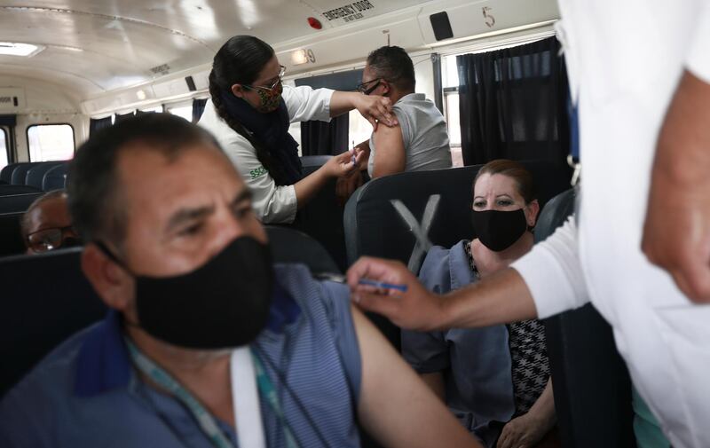 A health worker administers the Pfizer vaccine to maquiladora workers in a bus outside the Benito Juarez Olympic Stadium in Ciudad Juarez, Mexico. AP Photo