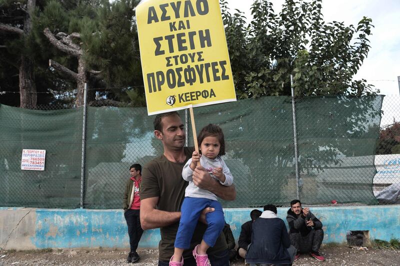 A child holds a banner reading "Asylum and shelter for refugees" as an anti-racist group protests in solidarity with refugees and migrants outside the refugee's camp of Diavata, west of Thessaloniki, on November 10, 2019.  Hundreds of inhabitants of Diavata protested against the refugee camp in their area on November 9, 2019. / AFP / Sakis MITROLIDIS
