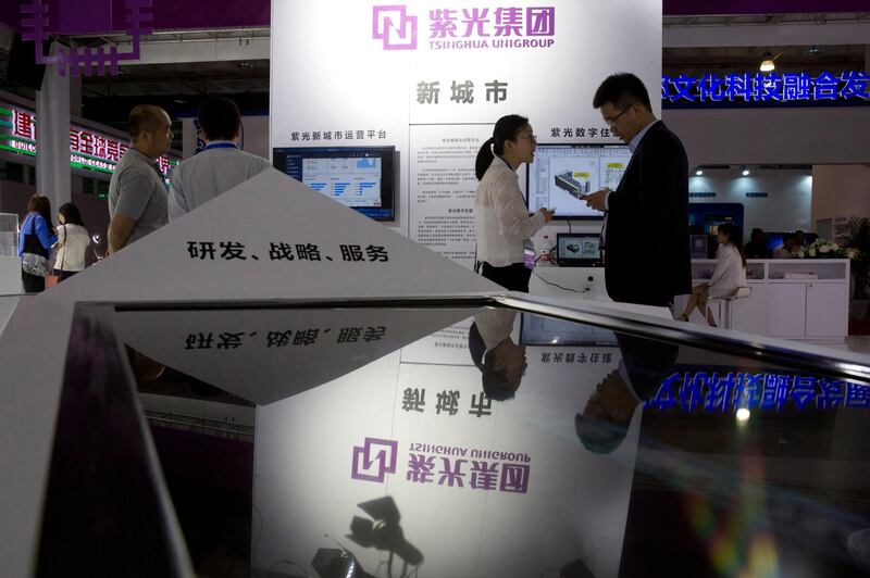 Attendees at the 21st China Beijing International High-tech Expo look at the booth of the state-controlled Tsinghua Unigroup project.  Ng Han Guan / AP Photo