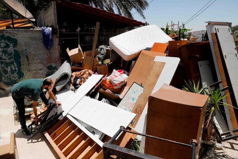 A Palestinian member of the Siyam family arranges furniture that was thrown out of their home during their eviction, in the Palestinian neighbourhood of Silwan in east Jerusalem near the Old City on July 10, 2019. The Palestinian Siyam family was evicted on July 10, after Israeli settlers won a court battle that stretched more than two decades. The Silwan apartment was home to a 53-year-old woman and her four children, according to Israeli NGO Peace Now, which opposes Israeli settlement expansion. Police arrived and evicted the residents from the apartment and they will at least temporarily stay with relatives. An Israeli court found that the Elad foundation, which seeks to increase the Jewish presence in mainly Palestinian east Jerusalem, had legally purchased that portion of the property and ruled in its favour. / AFP / AHMAD GHARABLI
