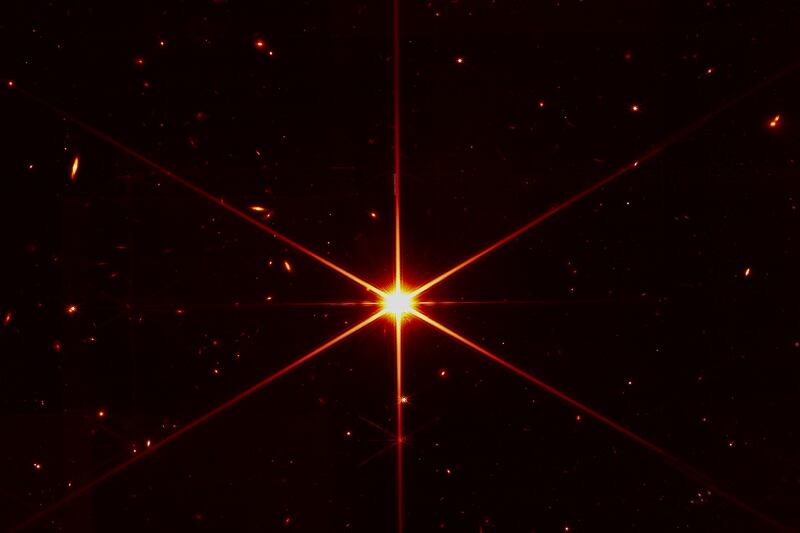 This image made available by Nasa on March 16, 2022 shows star 2MASS J17554042+6551277 used to align the mirrors of the James Webb Space Telescope, with galaxies and stars surrounding it.  The hexagonal shape of Webb’s mirrors and its filters made the shimmering star look more red and spiky.  The first science images aren't expected until July 12. Photo: Nasa 