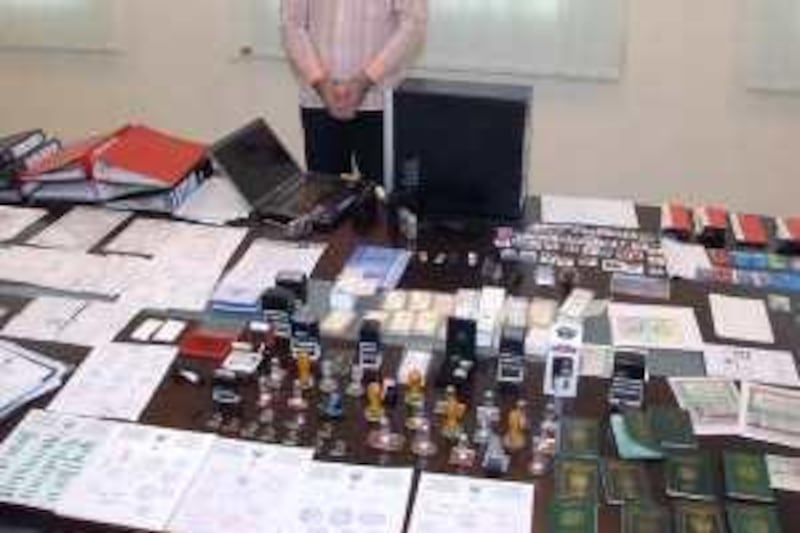 A suspect is posed in front of fake credit cards, chequebooks, passports and visas that were seized by Sharjah Police, leading to the arrest of two suspects. Courtesy Ministry of Interior