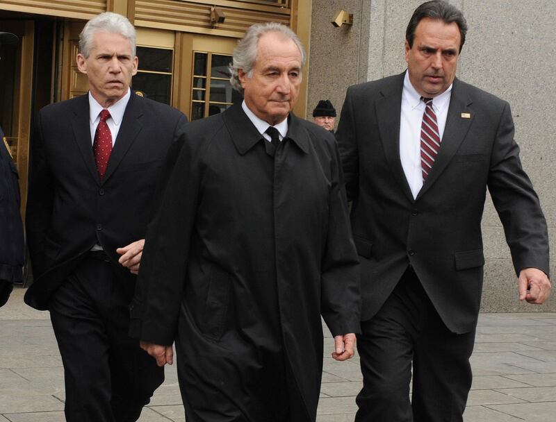 FILE - In this March 10, 2009 file photo, Bernard Madoff, center, exits Manhattan federal court in New York. Madoff, who pleaded guilty in 2009 to orchestrating the largest Ponzi scheme in history, is seeking an early release from prison. The Department of Justice confirmed on Wednesday, July 24, 2019 that Madoff has a pending request to get his 150-year sentence reduced. (AP Photo/Louis Lanzano, file)