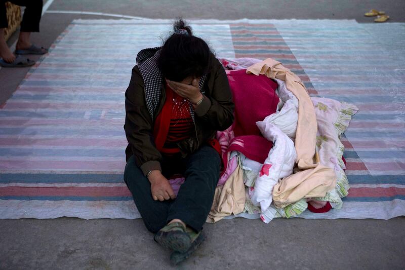 Ren Shuyong, 48, cries as she sits outside near Shangli town in southwestern China's Sichuan province, Sunday, April 21, 2013. Residents awoke Sunday after spending the night outdoors or in their cars in a town near the epicenter of a powerful earthquake that struck the steep hills of China's southwestern Sichuan province, leaving at least 160 people dead and more than 6,700 injured. (AP Photo/Ng Han Guan) *** Local Caption ***  APTOPIX China Earthquake.JPEG-05c76.jpg